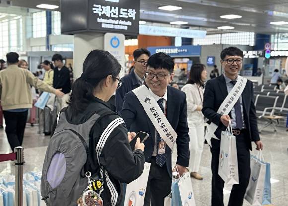 24일 청주국제공항 입국장에서 공항공사 관계자들이 춘추항공 이용객에게 기념품을 주고 있다. [사진=한국공항공사 청주공항]