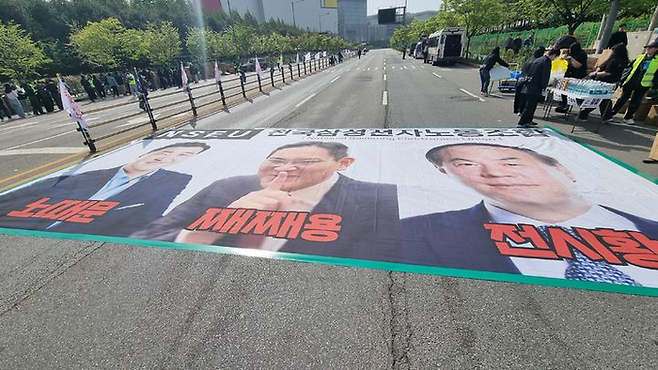 23일 경기 평택시 고덕동 삼성전자 평택캠퍼스에서 열린 삼성전자 노동조합 공동투쟁본부 ‘4·23 투쟁 결의대회’에서 이재용 삼성전자 회장, 전영현 삼성전자 대표이사 부회장, 노태문 삼성전자 사장의 사진 현수막이 바닥에 놓였다. [뉴시스]