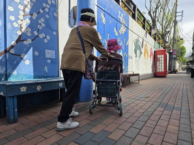 대구 중구 '김광석 다시그리기길' 벽화 골목에서 요양보호사가 실버카(보행보조기)를 탄 노인을 밀며 산책하고 있다. 김광석 길은 보행로가 평탄해 실버카나 고령자가 접근하기에는 비교적 편리하다. 하지만 휠체어를 탄 중증 장애인은 거의 찾아볼 수 없어, 진정한 무장애 관광지가 되기 위해서는 여전히 개선해야 할 과제가 많음을 시사한다. 김용국 기자