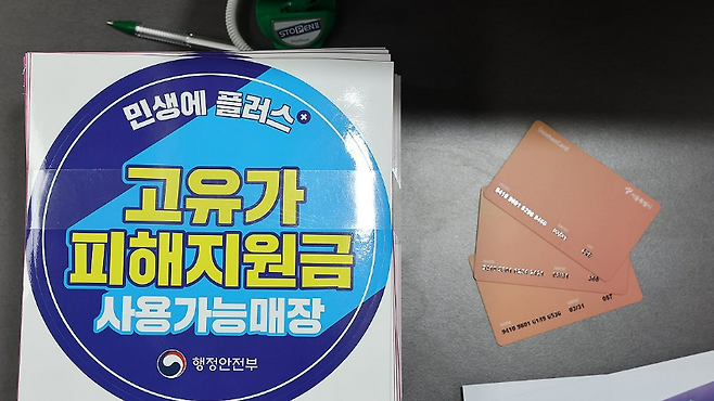 지난 24일 서울 숭인2동주민센터에 마련된 고유가 피해지원금 신청 창구에 관련 부착물과 사용 카드가 놓여 있다. /연합뉴스