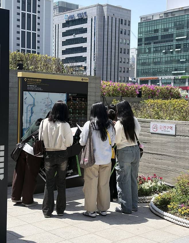 지난 24일 '더 스카우트 in 부산' 프로그램 참여자들이 첫 코스인 부산역 광장에서 퀴즈를 풀고 있는 모습. 부산관광공사 제공