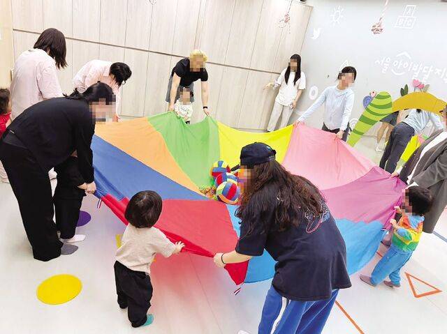 서울시가 위탁·운영하는 서울아이발달지원센터에서 발달놀이터 프로그램에 참여한 영유아와 부모들이 알록달록한 색깔 천을 나눠 잡고 있다. 서울시는 다문화 가정을 대상으로 ‘찾아가는 발달검사’를 우선 지원하는 등 관련 정책을 강화한다는 방침이다. 서울시 제공