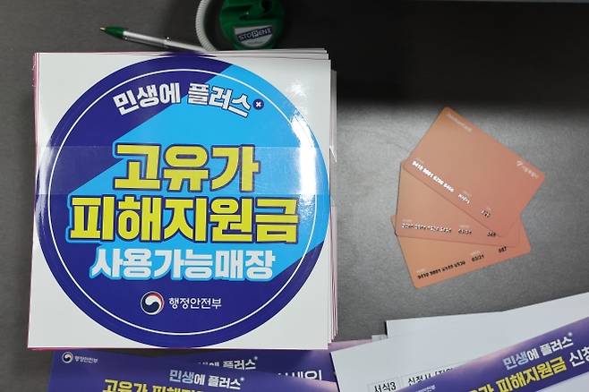 27일부터 고유가 피해지원금 지급 - 24일 서울 숭인2동주민센터에 마련된 고유가 피해지원금 신청 창구에 관련 부착물과 사용 카드가 놓여 있다. 고유가 피해지원금은 이달 27일부터 5월 8일까지 기초생활수급자·차상위가구·한부모가족을 대상으로 우선 지급한다. 연합뉴스