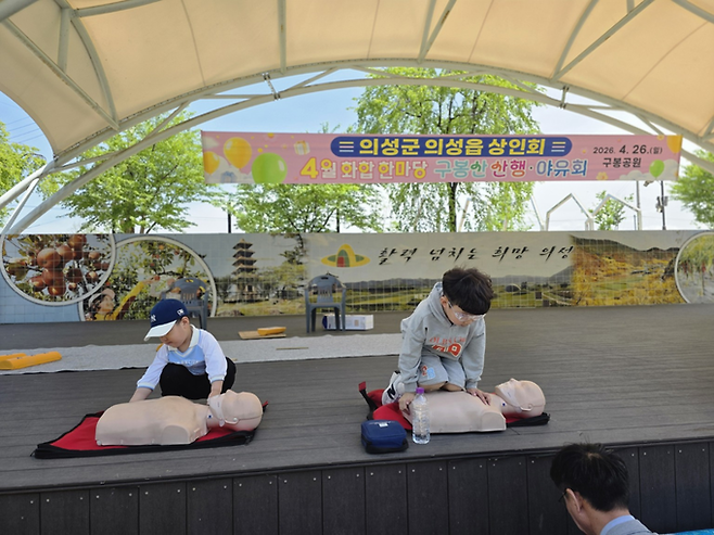 ▲ 26일 경북 의성군 구봉공원 상설무대 앞에서 열린 의성군 의성읍 상인회 산행·야유회에서 어린이들이 심폐소생술 체험을 하고 있다. 이날 행사는 출범 이후 첫 단합 행사로, 회원과 가족 등 40여 명이 참여해 산행과 환경정비, 안전교육, 윷놀이 등을 함께했다. 김동현 기자 jhass80@kyongbuk.com