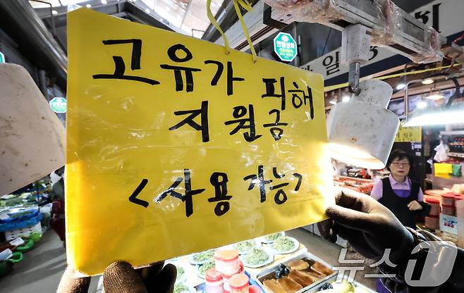 고유가 피해지원금 1차 지급 신청일인 27일 서울 동대문구 경동시장 한 점포에서 직원이 ’고유가 피해지원금 사용 가능‘ 안내문을 게시하고 있다. 2026.4.27 ⓒ 뉴스1 임지훈 인턴기자