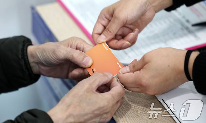 고유가 피해지원금 1차 지급이 시작된 27일 서울 강서구 화곡4동 주민센터에서 직원이 고유가 피해지원금을 시민에게 전달하고 있다. 2026.4.27 ⓒ 뉴스1 박지혜 기자