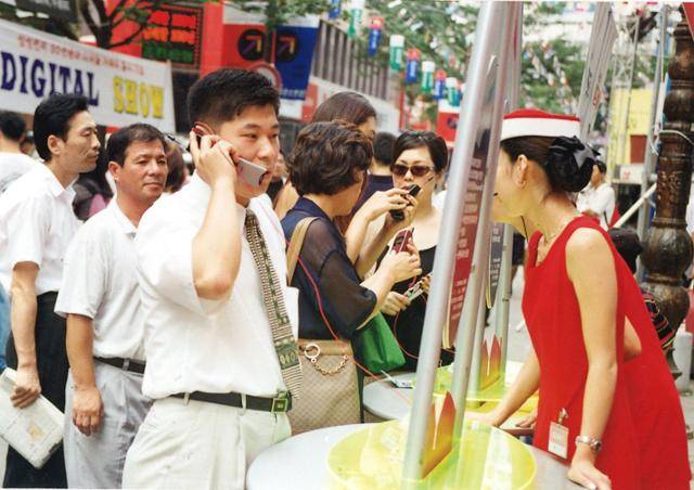 한 시민이 PCS 도입 당시 서울 명동에서 벌어진 PCS업체의 길거리 판촉 행사에서 PCS 휴대폰을 시연해 보고 있다. 한국일보 자료사진