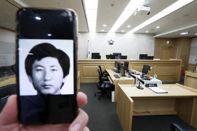 '이춘재 연쇄살인' 9차 사건 범인으로 억울하게 구속 수사를 받았던 고(故) 윤동일 씨가 재심에서 '무죄'를 선고 받았다. 사진은 휴대폰에 담긴 이춘재 얼굴과 그가 2020년 11월2일 증인으로 출석했던 경기도 수원시 영통구 수원지방법원 501호 법정.(사진=뉴시스)