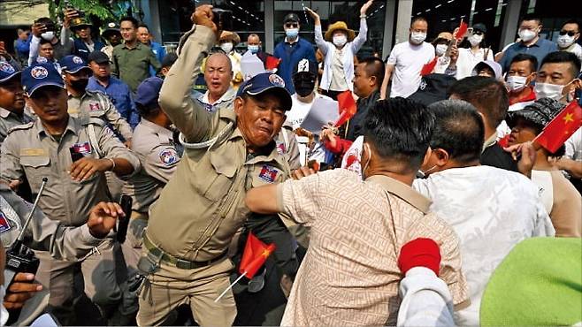 캄보디아 결제 서비스 ‘후이원페이’ 이용자들이 27일 프놈펜에서 시위를 벌이다가 경찰과 몸싸움하고 있다. 이들은 불법 자금을 세탁한 혐의로 동결된 은행 계좌를 해제해 달라고 요구했다.   AFP연합뉴스