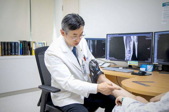 강현귀 국립암센터 육종암센터 교수가 골육종 제거 후 환자 맞춤형 3D프린팅 골 재건 수술을 받은 10대의 다리를 살펴보고 있다.