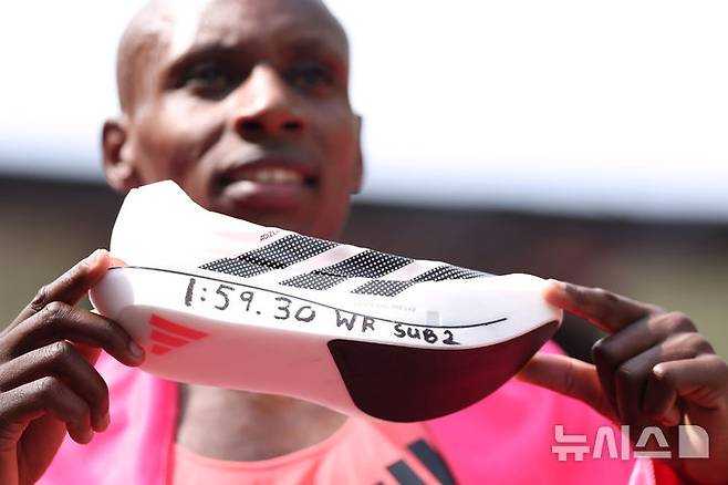 [런던=AP/뉴시스] 사바스티안 사웨(케냐)가 26일(현지 시간) 영국 런던에서 열린 2026 런던마라톤에서 1시간 59분 30초 세계신기록으로 결승선을 통과한 뒤 기록이 적힌 신발을 들고 포즈를 취하고 있다. 2026.04.26.
