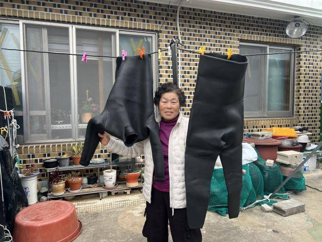 여수시 남면 안도에서 만난 물질 57년차 한준자 해녀가 해녀복 옆에서 환하게 웃어보이고 있다.