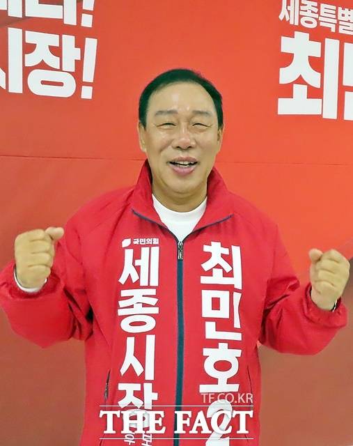 최민호 예비후보가 선거사무소 대형 현수막 앞에서 파이팅을 외치고 았다. /김형중 기자