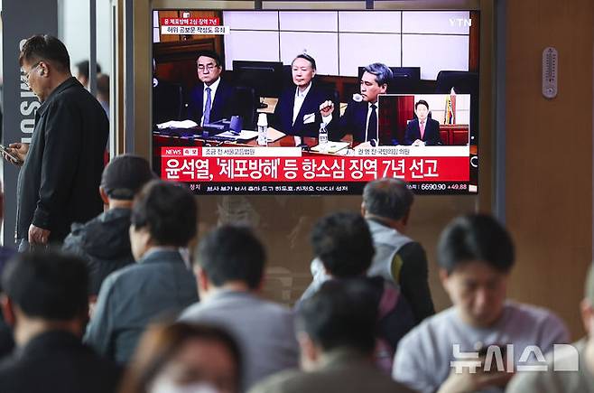 [서울=뉴시스] 조성우 기자 = 29일 오후 서울 중구 서울역 대합실에서 시민들이 체포 방해 및 국무위원 심의권 침해 혐의로 기소된 윤석열 전 대통령에 대한 2심 선고 공판 생중계를 보고 있다. 2026.04.29. xconfind@newsis.com