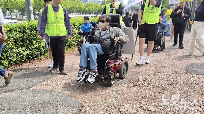 29일 오전 10시 40분쯤 광주 서구 유스퀘어 터미널 앞에서 장애인단체 회원이 휠체어를 타고 행진하고 있다. 울퉁불퉁하게 파손된 인도 위에서 휠체어가 휘청거리고 있다. 한아름 기자