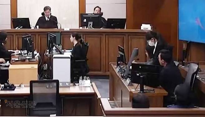 김건희 여사가 28일 서울 서초구 서울고등법원에서 열린 항소심 재판에서 마스크와 안경을 쓴 채 일어나 고개를 숙인 자세로 재판부의 형량 선고를 듣고 있다. 서울중앙지법 제공