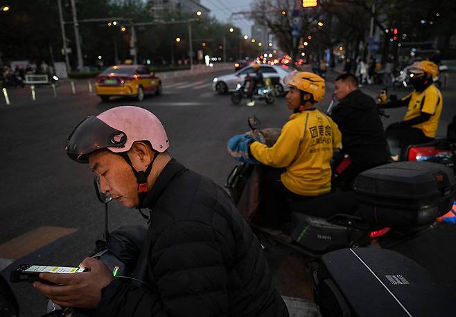 중국 베이징 산리툰 상업지구에서 배달 기사들이 대기하고 있다. 중국내 온라인 플랫폼 노동자는 2억명을 넘어설 정도로 규모가 늘었지만 처우가 미흡하다는 지적이 잇따르면서, 최근 당국이 플랫폼 노동자 보호 계획을 발표했다.