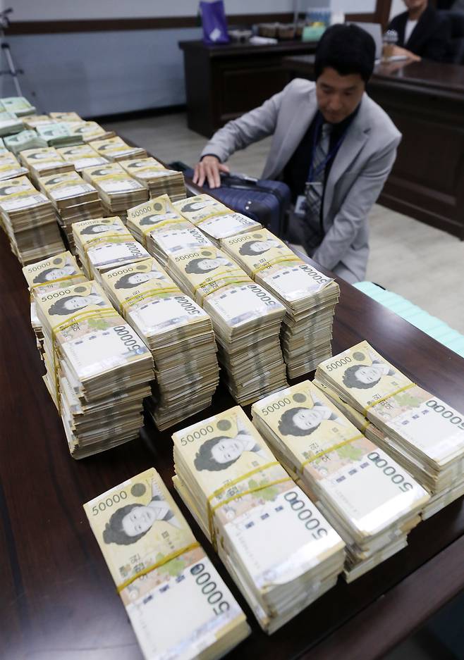 2023년 10월 서울 강북경찰서에서 경찰이 국내에서 가상자산을 매수 후 해외 거래소에서 팔아 수백억원의 자금을 빼돌린 혐의를 받는 국제 환치기 범죄조직으로부터 압수한 현금 및 물품을 정리하고 있다.  사진은 기사 내용과 관계없음. / 뉴스1