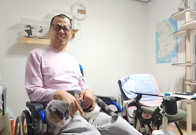 뇌병변 장애인 김현수씨가 4월 28일 서울 동대문구 장안동 자신의 집 거실에서 반려묘 메주와 포즈를 취하고 있다. 이재덕 기자