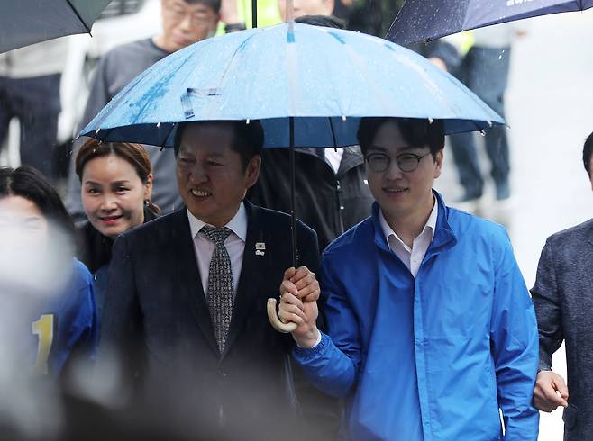 더불어민주당 정청래 대표와 부산 북구갑 국회의원 보궐선거에 출마하는 하정우 전 청와대 AI미래기획수석이 3일 함께 우산을 쓰고 부산 북구 구포시장으로 이동하고 있다. 뉴스1