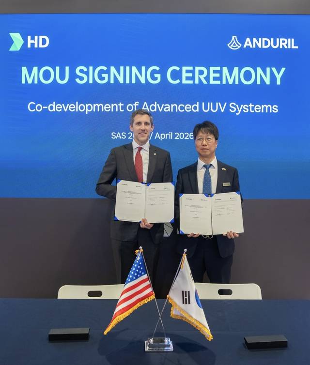 지난 4월 22일 HD현대가 미국 워싱턴DC에서 열린 ‘2026 해양항공우주 전시회(SAS 2026)’ 전시관에서 미국 인공지능(AI) 방산 기업인 안두릴 인더스트리와 무인잠수정(UUV) 개발 협력에 관한 MOU를 체결했다. 이상봉(오른쪽) HD현대중공업 함정사업본부 함정설계 부문장(상무)과 앤드류 너스 안두릴 해양사업 총괄본부장이 기념 사진을 촬영하고 있다. HD현대 제공
