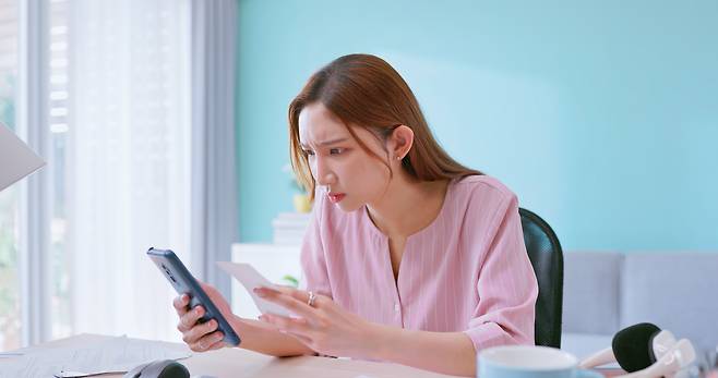 한 여성이 핸드폰을 보며 의아한 표정을 짓고 있다. 게티이미지뱅크