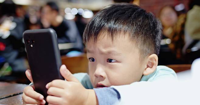 스마트폰을 쳐다보는 아이의 이미지. 클립아트코리아