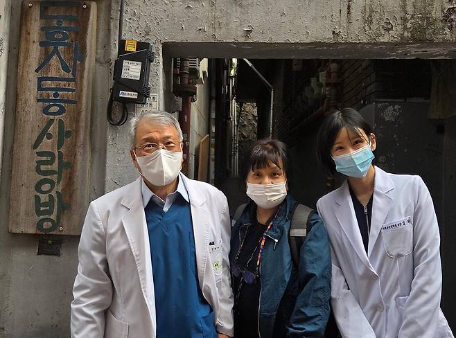 지난 4월 28일 서울 용산구 동자동 쪽방촌으로 방문진료에 나선 고영초(왼쪽) 요셉의원 원장이 주민조합 시설 앞에서 전공의 김완(오른쪽)씨, 자원봉사자와 함께 포즈를 취하고 있다. 나민서 기자