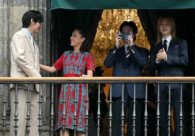 뒤편에 선 클라우디아 셰인바움 멕시코 대통령을 앞으로 이끄는 방탄소년단 뷔의 모습. [AFP]
