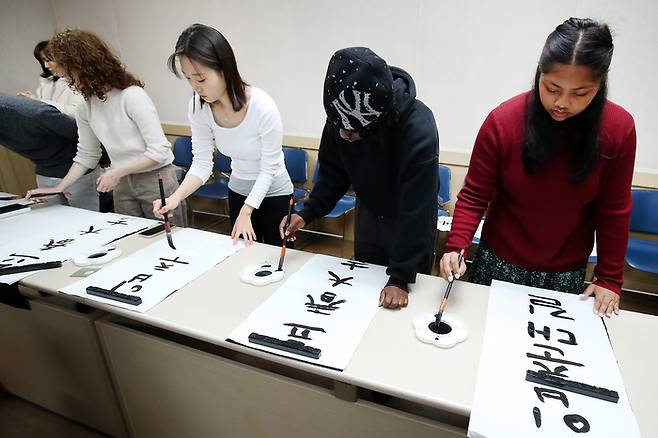 한국 전통문화 체험에 참여한 외국인 유학생들이 한글과 한자를 붓글씨로 쓰고 있다. [뉴스1]