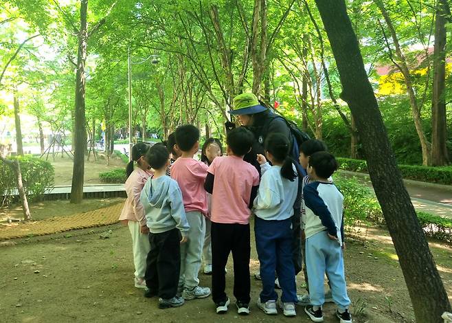 ▲&nbsp;민백초등학교 학생들이 민백공원에서 '숲에서 배우는 생태계'&nbsp;수업을 듣고 있다. /사진제공=민백초등학교