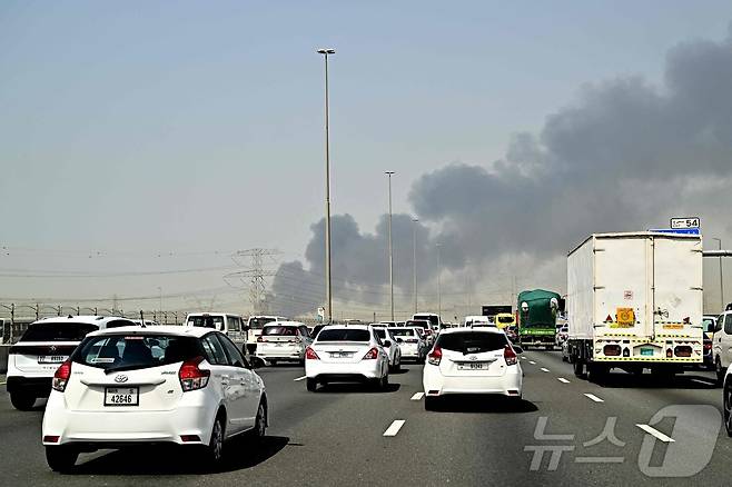 지난 3월 16일(현지시간) 아랍에미리트(UAE) 두바이 국제공항 인근에서 발생한 화재로 인해 자욱한 연기가 피어오르는 모습이 고속도로에서 보이고 있다. 공항 운영사는 인근 연료 탱크에서 발생한 "드론 관련 사건"으로 인한 화재 이후 항공편 운항이 3월 16일부터 점차 재개되고 있다고 밝혔다. 2026.03.16. ⓒ AFP=뉴스1
