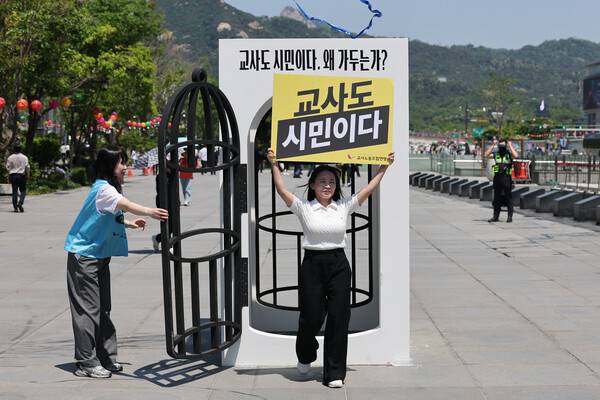 스승의 날을 하루 앞둔 14일 서울 종로구 광화문광장에서 교사노조연맹 주최로 열린 교사 시민권 회복 행사에서 송수연 교사노조연맹 위원장이 '새장에 갇힌 교사 시민권' 퍼포먼스를 마치고 새장 모형에서 나오고 있다. 2026.5.14 연합뉴스