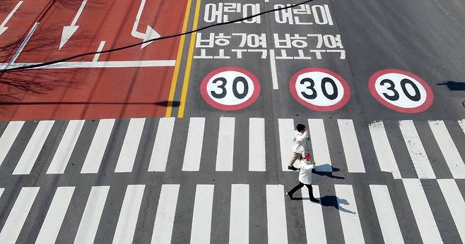 어린이들이 손을 들고 횡단보도를 건너고 있다. 어린이보호구역 교통사고를 막기 위해 2020년부터 '민식이법'이 시행되었다. /김영근 기자