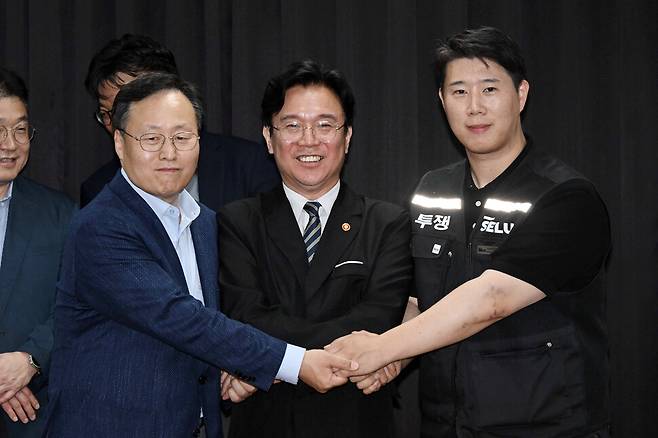 삼성전자 노사 협상이 잠정 합의된 20일 경기도 수원시 장안구 경기지방고용노동청에서 김영훈 고용노동부 장관(앞줄 가운데), 최승호 삼성전자 노조 공동투쟁본부 위원장(맨오른쪽), 여명구 DS(디바이스솔루션·반도체 사업 담당) 피플팀장이 손을 맞잡고 있다. 이날 삼성전자 노사는 김영훈 고용노동부 장관의 중재로 다시 임금협상에 나섰다. 공동취재사진