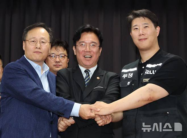 [수원=뉴시스] 김종택기자 = 20일 경기 수원시 장안구 경기고용노동청에서 열린 삼성전자 임금협상을 마친 후 여명구 삼성전자 DS(디바이스솔루션·반도체 사업 담당) 피플팀장(왼쪽부터)과 김영훈 고용노동부 장관, 최승호 삼성그룹 초기업노동조합 삼성전자지부 위원장이 잠정 합의한에 서명한 후 손을 맞잡고 파이팅을 외치고 있다. (공동취재) 2026.05.20. photo@newsis.com