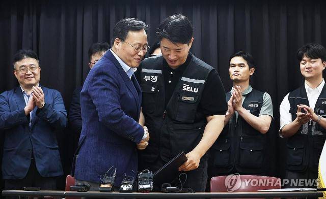 20일 경기도 수원시 장안구 경기고용노동청에서 열린 삼성전자 임금협상을 마친 후 여명구 삼성전자 DS(디바이스솔루션) 피플팀장과 최승호 삼성그룹 초기업노동조합 삼성전자지부 위원장이 잠정 합의안에 서명한 후 손을 맞잡고 있는 모습 [사진=연합뉴스]