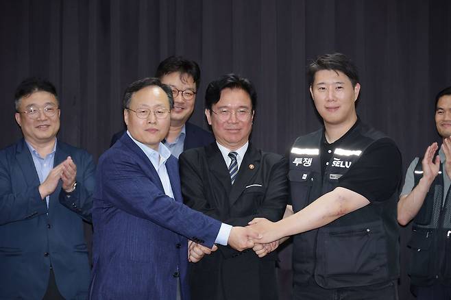 20일 경기도 수원시 장안구 경기고용노동청에서 열린 삼성전자 임금협상을 마친 후 여명구 삼성전자 DS(디바이스솔루션 반도체 사업 담당) 피플팀장과 김영훈 고용노동부 장관, 최승호 삼성그룹 초기업노동조합 삼성전자지부 위원장이 잠정 합의한에 서명한 후 손을 맞잡고 있다. 김성룡 기자
