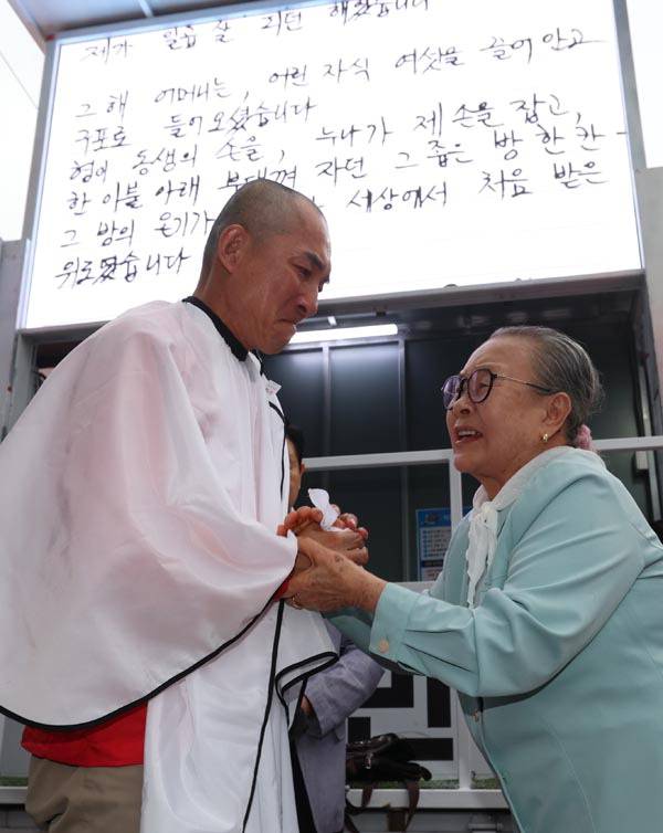 국민의힘 박민식 부산 북갑 보궐선거 후보가 21일 부산 구포시장 쌈지공원에서 열린 출정식에서 삭발한 뒤 어머니와 손을 잡고 있다. 박 후보는 삭발하며 "배신자 한동훈과 단일화하지 않겠다"고 말했다. 연합뉴스