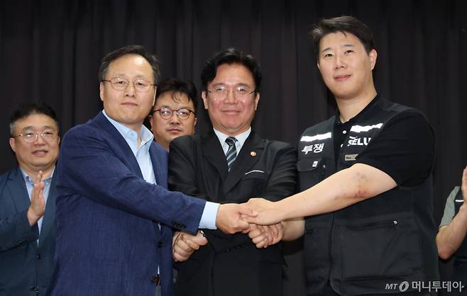 [수원=뉴시스] 김종택기자 = 20일 경기 수원시 장안구 경기고용노동청에서 열린 삼성전자 임금협상을 마친 후 여명구 삼성전자 DS(디바이스솔루션·반도체 사업 담당) 피플팀장(왼쪽부터)과 김영훈 고용노동부 장관, 최승호 삼성그룹 초기업노동조합 삼성전자지부 위원장이 잠정 합의한에 서명한 후 손을 맞잡고 있다. (공동취재) 2026.05.20. photo@newsis.com /사진=김종택