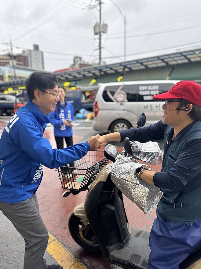 6·3 지방선거 공식 선거운동 첫날인 21일 오전 최동민(왼쪽) 더불어민주당 서울 동대문구청장 후보가 동대문구 제기동 경동시장을 찾아 한 상인과 인사를 나누며 선거운동을 하고 있다. [최동민 후보 캠프 제공]