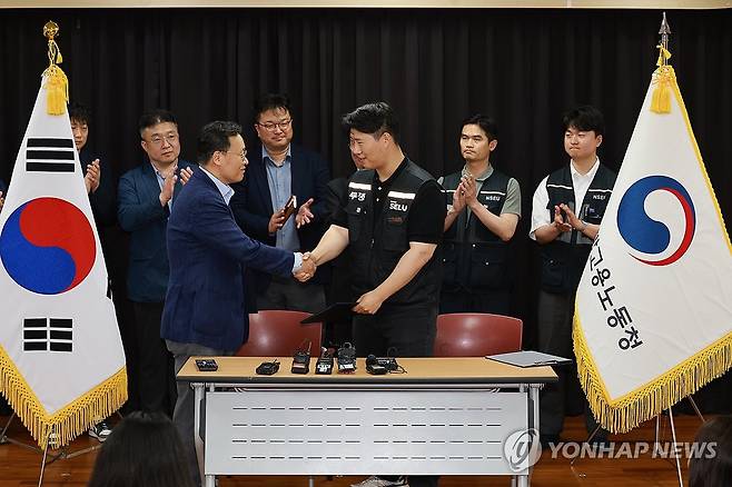 삼성전자 임금협상 잠정 합의 (수원=연합뉴스) 홍기원 기자 = 20일 경기도 수원시 장안구 경기고용노동청에서 열린 삼성전자 임금협상을 마친 후 여명구 삼성전자 DS(디바이스솔루션·반도체 사업 담당) 피플팀장과 최승호 삼성그룹 초기업노동조합 삼성전자지부 위원장이 잠정 합의안에 서명한 후 손을 맞잡고 있다. 2026.5.20 [공동취재] xanadu@yna.co.kr