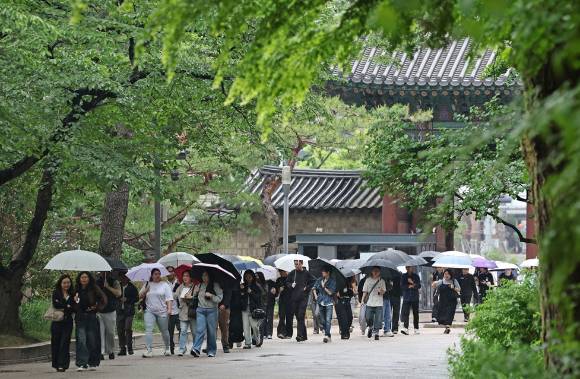 비가 내린 가운데 서울 덕수궁에서 외국인 관광객들이 우산을 쓰고 길을 걷고 있다. [사진=연합뉴스]