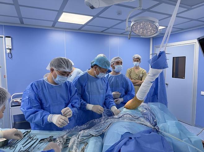 지난 21일(현지시간) 우즈베키스탄 타슈켄트 기묘대학교 대학병원에서  대한정형외과의사회(회장 김완호) 소속 의사들이 40대 여성 환자의 어깨 수술을 집도하고 있다. [사진 = 통일문화연구원 ]