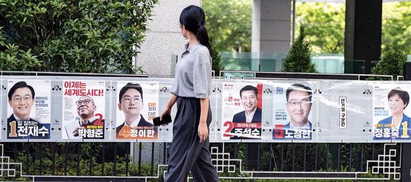 6·3 전국동시지방선거를 9일 앞둔 25일 부산 연제구에서 유권자가 건물 담벼락에 붙은 선거 벽보를 살펴보고 있다.  전민철 기자