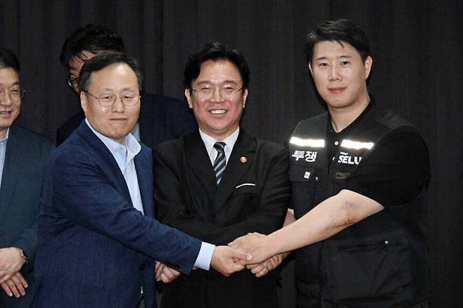 지난 20일 경기 수원시 장안구 경기고용노동청에서 열린 삼성전자 임금협상을 마친 후 여명구 삼성전자 DS(디바이스솔루션·반도체 사업 담당) 피플팀장과 김영훈 고용노동부 장관, 최승호 삼성그룹 초기업노동조합 삼성전자지부 위원장이 잠정 합의한에 서명한 후 손을 맞잡고 있다. 뉴스1