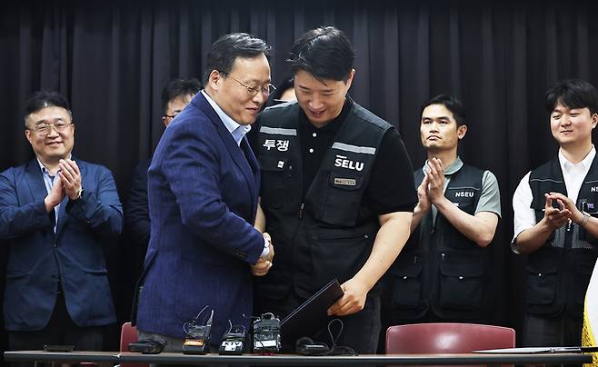 20일 경기도 수원시 장안구 경기고용노동청에서 열린 삼성전자 임금협상을 마친 후 여명구 삼성전자 DS(디바이스솔루션·반도체 사업 담당) 피플팀장과 최승호 삼성그룹 초기업노동조합 삼성전자지부 위원장이 잠정 합의안에 서명한 후 손을 맞잡고 있다. [공동취재]