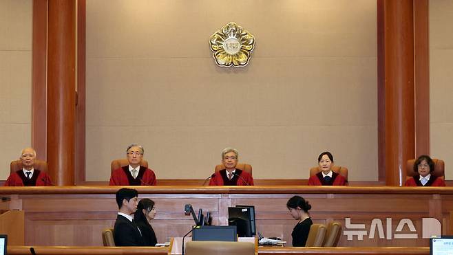 [서울=뉴시스] 이영환 기자 = 한국여성변호사회(여변) 등 여성단체가 아동 성범죄를 저지른 교사 등 신고 의무자를 가중 처벌하도록 정한 형벌 조항을 헌법재판소가 위헌 결정한 데 대해 우려를 표명했다. 김상환 헌법재판소장과 헌법재판관들이 지난 21일 오후 서울 종로구 헌법재판소 심판정에서 열린 5월 심판사건 선고에 참석해 자리에 앉아 있다. 2026.05.26. 20hwan@newsis.com