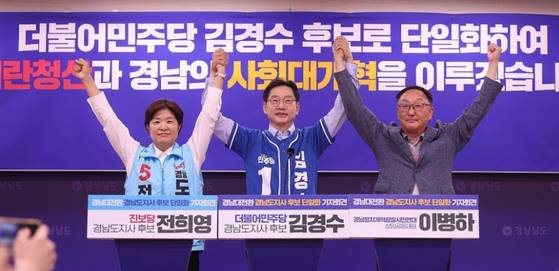 더불어민주당 김경수 경남지사 후보와 진보당 전희영 후보가 27일 경남도청 프레스센터에서 열린 '경남대전환 경남도지사 후보 단일화' 긴급 기자회견에서 손을 들어 인사하고 있다. 두 정당은 김경수 후보로 단일화했다. 왼쪽부터 전 후보, 김 후보, 이병하 경남정치개혁광장시민연대 상임공동대표. 〈사진=연합뉴스〉