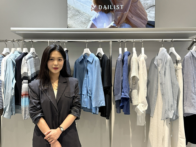 송채영 세정 웰메이드 마케팅팀 사원이 서울 강남구 사옥에서 자사 여성복 브랜드 ‘데일리스트’ 제품을 배경으로 포즈를 취하고 있다.  [세정 제공]